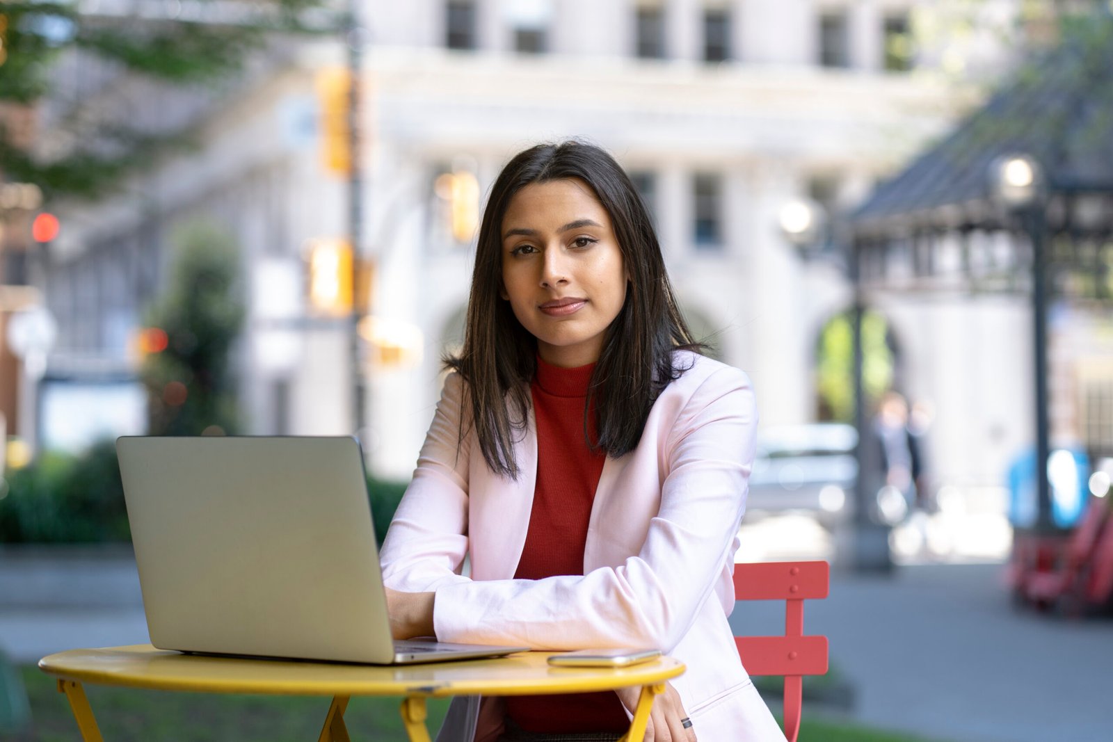 Portrait of young confident Indian businesswoman, freelancer using laptop computer looking at camera, working online sitting at workplace. Successful business