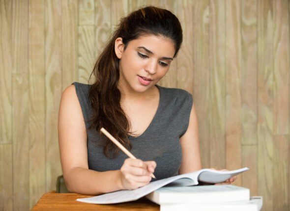 Portrait of smiling student writing in classroom